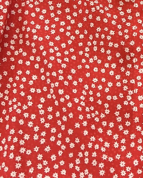 A close-up of the blouse fabric showing the small cream flowers on red.