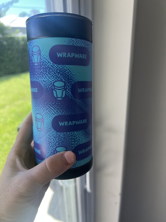 Second printed design: repeating Wrapware wordmarks and cup icons, photographed indoors by a window.