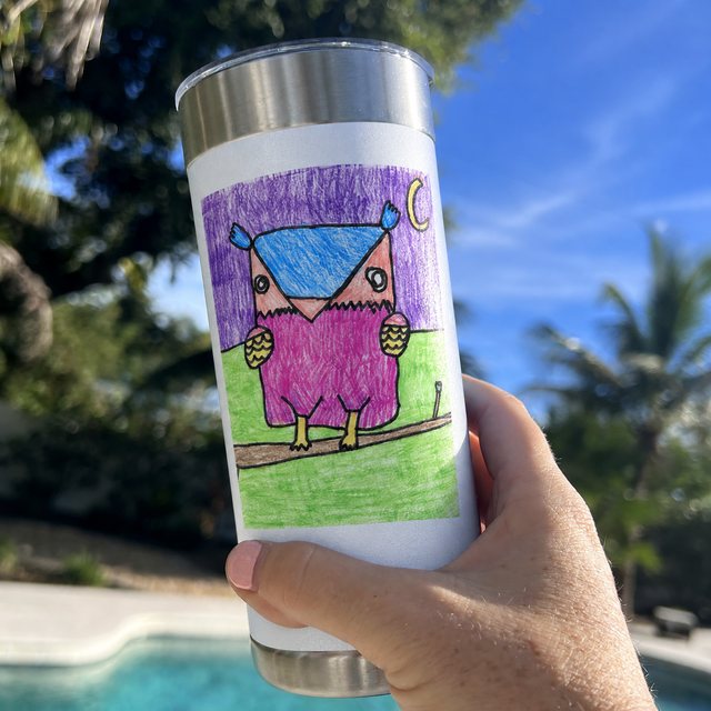 A real Wrapware tumbler held up by a pool, printed with the whole owl drawing on a white wrap (photo edit).